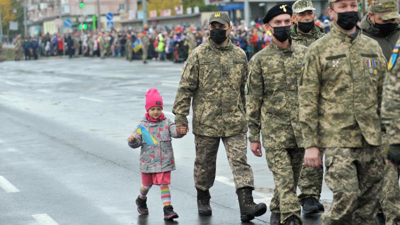 Ukrainas bruņoto spēku veterāns soļo kopā ar meitiņu parādē par godu Ukrainas aizstāvju dienai