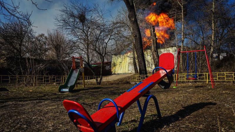 Tukšs rotaļlaukums Ukrainā, kura fonā ir Krievijas apšaudes izraisīts ugunsgrēks. Foto: Volodimira Zelenska "Telegram"/Ukrainska Pravda