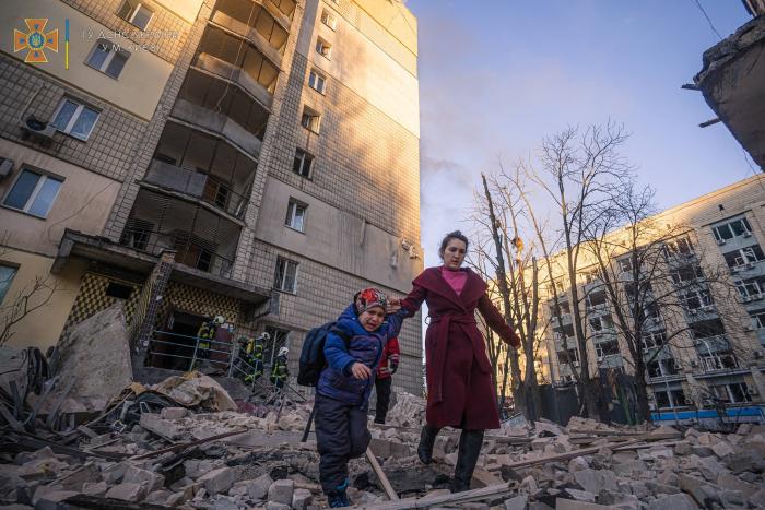 Sieviete ar bērnu evakuējas no Krievijas okupācijas spēku sabombardētās ēkas Kijivā