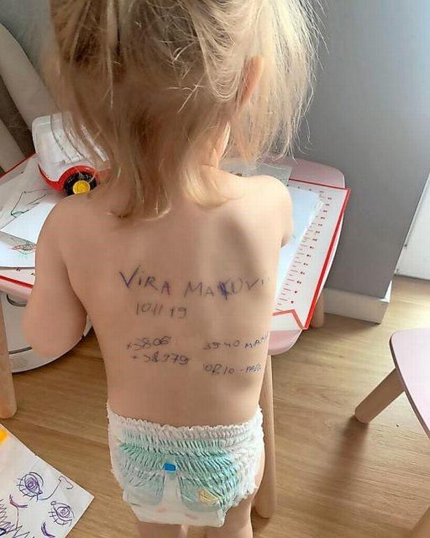 Uz pāris gadu vecas meitenītes muguras rakstīts viņas vārds un uzvārds, kā arī vecāku kontaktinformācija. Foto: Sasha Makoviy/PA Wire