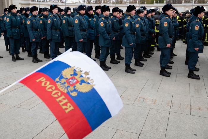 Cilvēks tur Krievijas karogu pie krievu karavīriem
