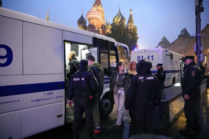 Policijas darbinieki pavada aizturētos demonstrantus uz policijas autobusu no protesta pret daļēju mobilizāciju Sarkanajā laukumā.
