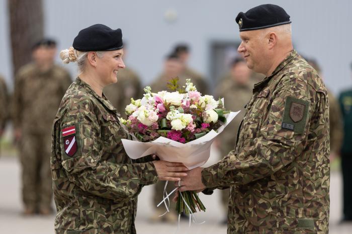 Aizejošais komandieris pasniedz ziedus jaunajai koamndierei