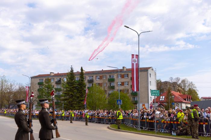 Virs klātesošajiem parādes skatītājiem pārliedo lidmašīna