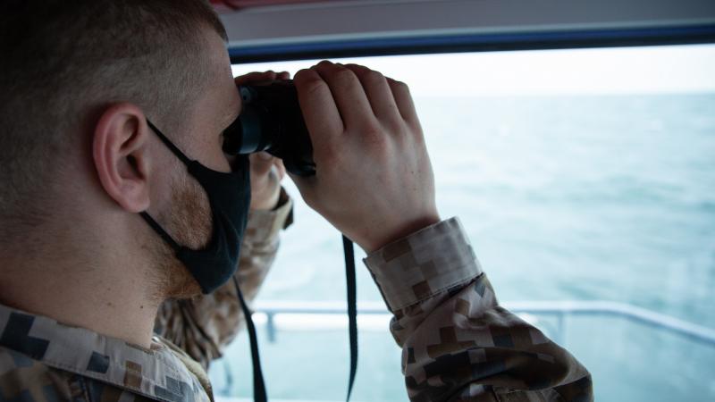 Jūrnieks skatās binoklī