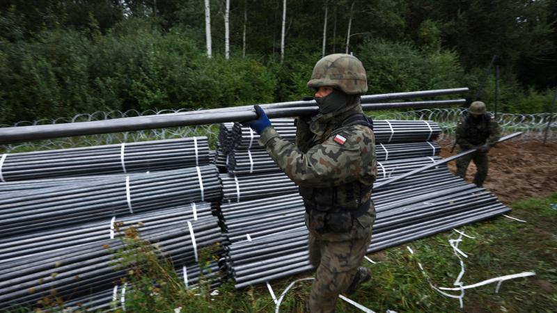 Polijas karavīri ceļ dzeloņstiepļu žogu uz robežas ar Baltkrieviju