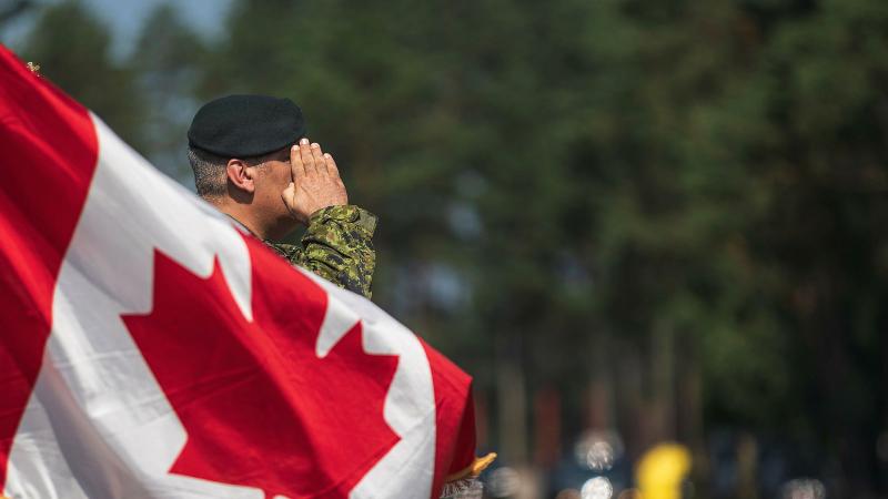 Kanādas karogs un karavīrs aiz tā