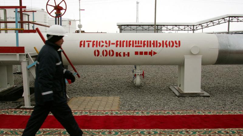 Kazahstānas naftas strādnieks iet garām naftas vadam