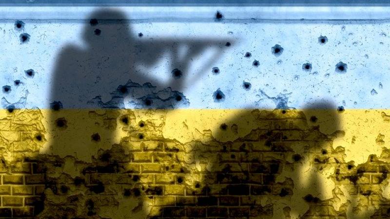 Ukrainas karogs un karavīru silueti uz sašautas sienas