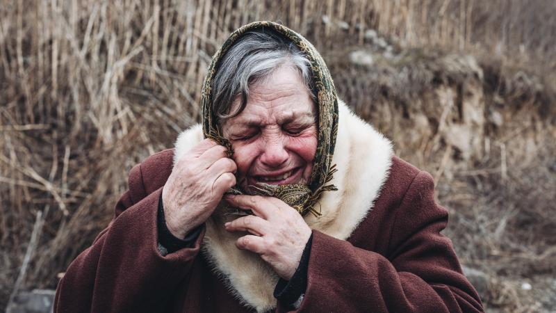 Ukraunas iedzīvotāja raud, izdzordot bombardēšanu