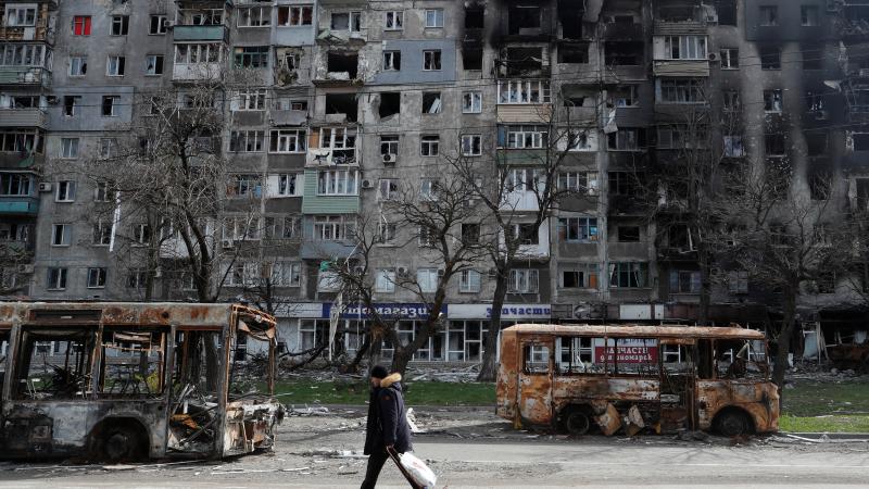 Ukrainas civiliedzīvotājs iet gar okupantu sagrautu dzīvojamo ēku