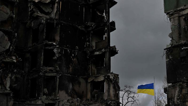 Ukrainas karogs, kas plīvo starp divām krievu iznīcinātām ēkām 