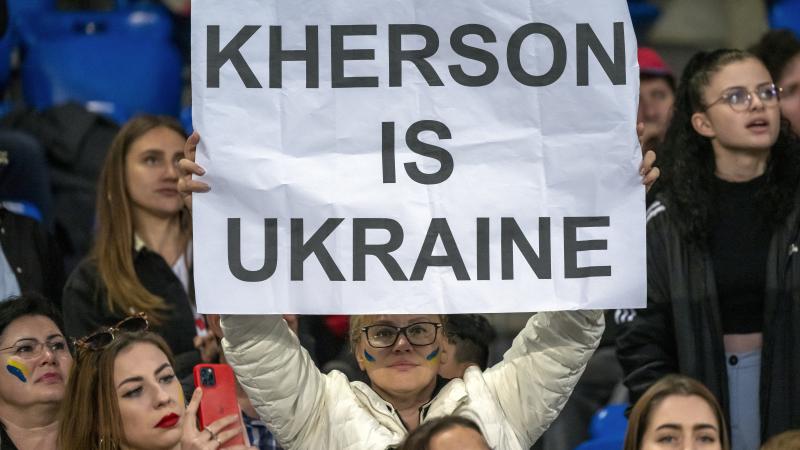 Sieviete tur rokās plakātu, uz kura rakstīts "Hersona ir Ukraina"