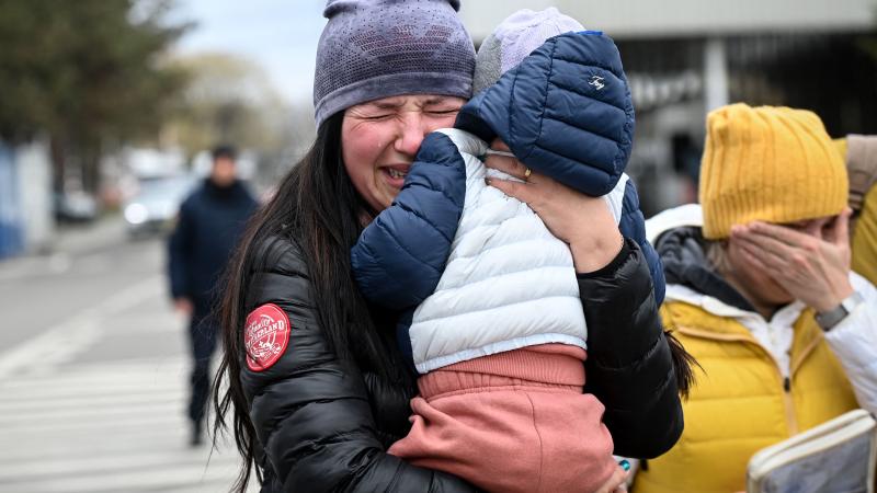 Ukraiņu bēgle, turot rokās savu bērnu, raud, ierodoties Sireta robežpunktā starp Rumāniju un Ukrainu 