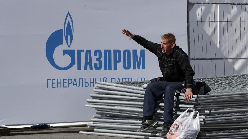 Krievu vīrietis Sanktpēterburgā pie "Gazprom" reklāmas plakāta