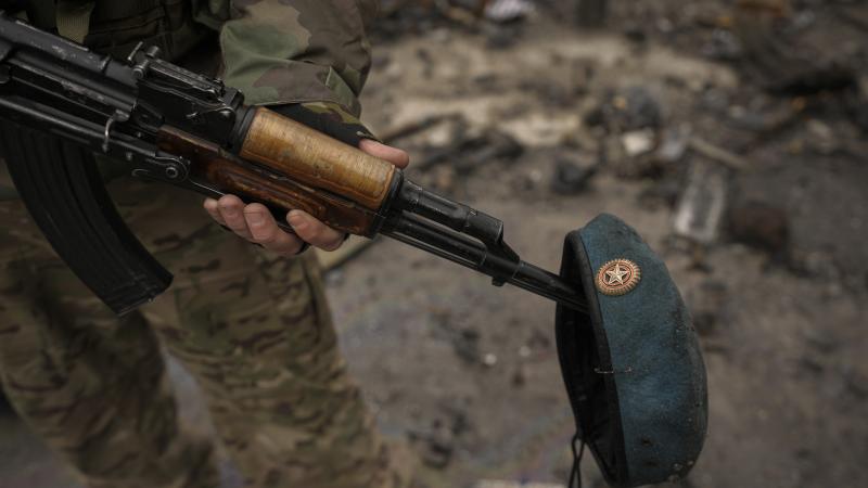 Ukrainas karavīrs ar ieroci tur Krievijas karavīra bereti