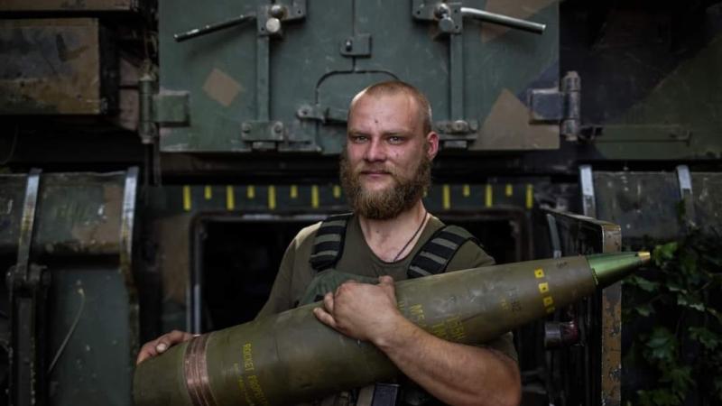 Ukrainas bruņoto spēku artilērists ar 155 milimetru haubices lādiņu