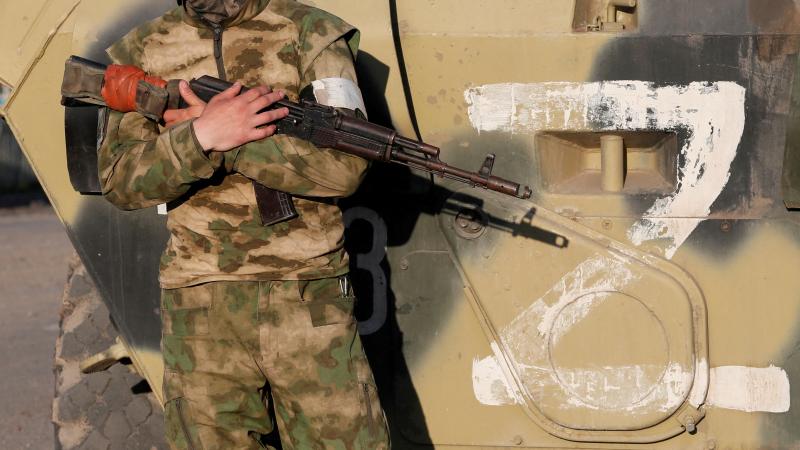 Krievu agresors Ukrainā stāv pie tehnikas, uz kuras uzzīmēts "Z" burts, kas ir iebrucēju pazīšanās zīme nelikumīgi iesāktajā karā pret Ukrainu