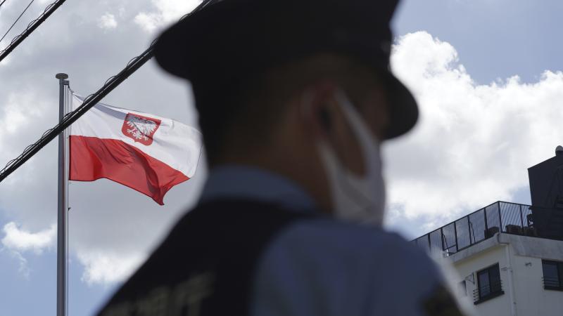 Polijas karogs, blakām esošs policists. 