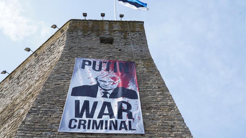 Igaunijas plakāts uz Narvas cietokšņa, atgādinot, ka Krievijas diktators Vladimirs Putins ir kara noziedznieks