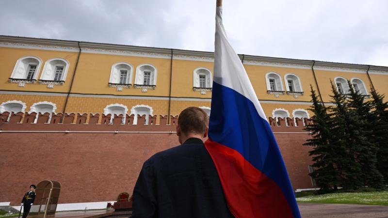 Krievijas iedzīvotājs ar valsts karogu pie Kremļa