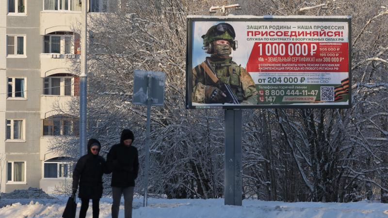 Krievijas iedzīvotāji iet garām reklāmai, kas aicina jauniešus iestāties armijā.