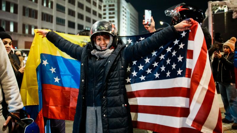 Sieviete tur Venecuēlas un ASV karogus