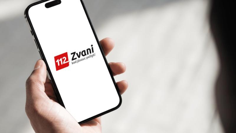 Cilvēks ar telefonu, kurā ir aplikācija "112"